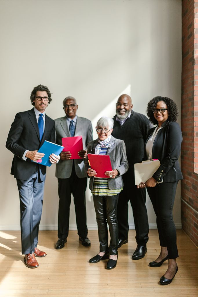 A diverse group of professionals holding folders and standing in a bright office setting.