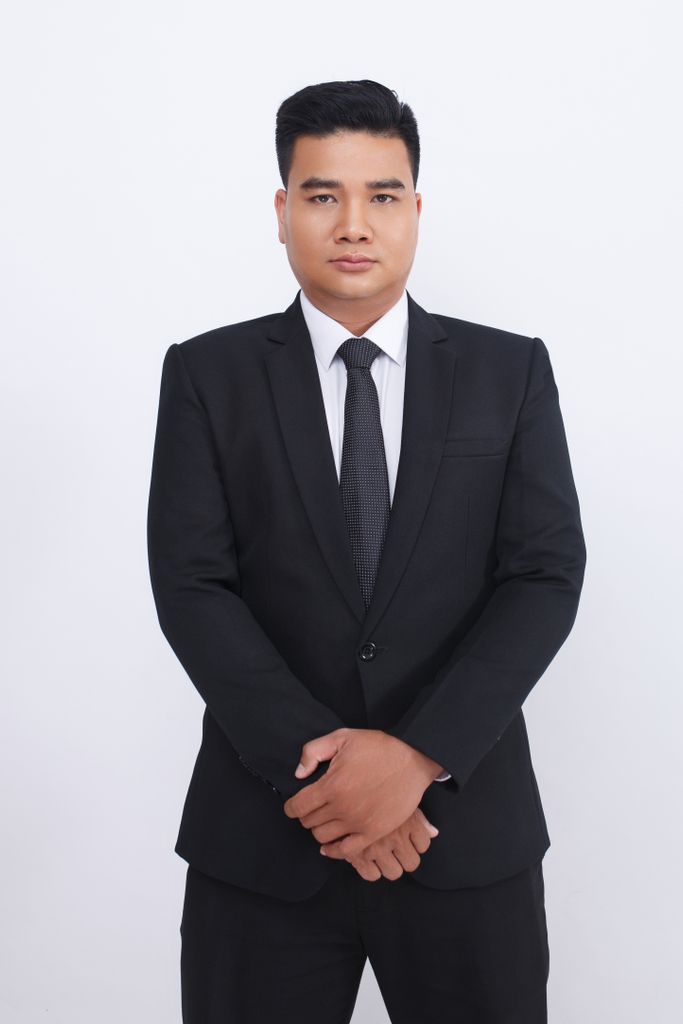 Confident businessman in a black suit and tie, looking directly at the camera, studio shot.
