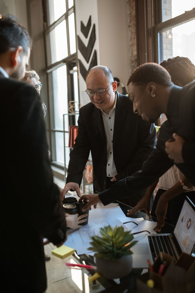 Diverse business team enjoying a coffee break while collaborating around a desk.