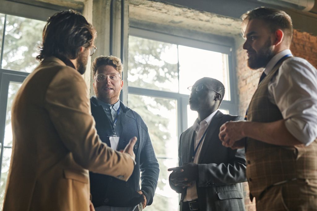 Group of men having a collaborative business meeting indoors with window views.