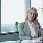 Professional businesswoman at a desk in a bright office with a laptop and notebook.